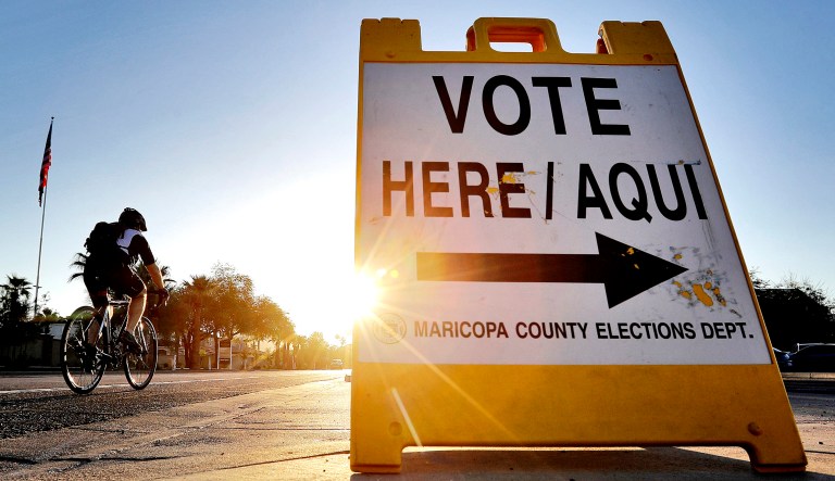 A cyclist rides past a sign directing voters to an election voting station in Phoenix.