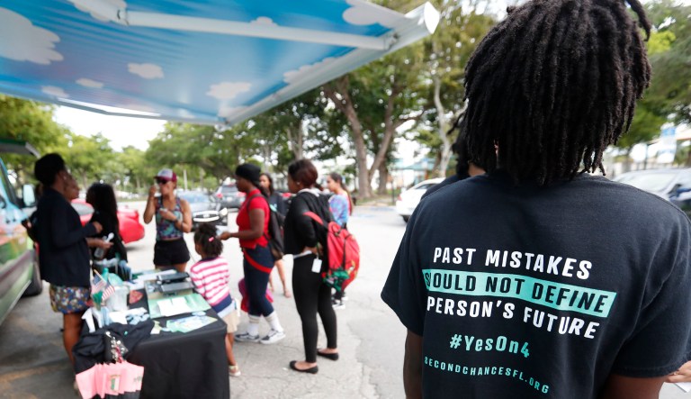 In this Oct. 22, 2018 file photo, people gather around the Ben & Jerry's "Yes on 4" truck as they learn about Amendment 4 and eat free ice cream at Charles Hadley Park in Miami. With a single vote Tuesday, Nov. 6, Florida added 1.4 million possible voters to the rolls when it passed Amendment 4, which said that most felons will automatically have their voting rights restored when they complete their sentences and probation.
