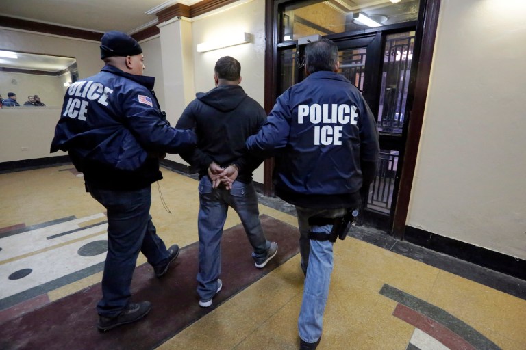 FILE- In this March 3, 2015 photo, Immigration and Customs Enforcement officers escort an arrestee in an apartment building, in the Bronx borough of New York, during a series of early-morning raids. New York City leaders are trying to strike a balance between purging dangerous criminals and protecting some of its roughly 500,000 undocumented immigrants.