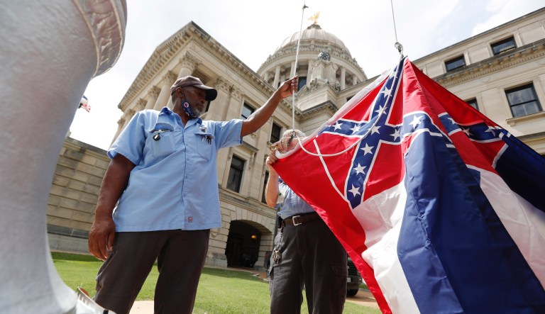 Mississippi Department of Finance and Administration employees Willie Townsend, left, and Joe Brown, attach a Mississippi state flag to the harness before raising it over the Capitol grounds in Jackson, Miss., Tuesday, June 30, 2020. The two men raised about 100 flags, provided by the Secretary of State's office, for people or organizations that purchased a state flag that flew over the grounds. Gov. Tate Reeves will sign a bill Tuesday evening retiring the last state flag with the Confederate battle emblem during a ceremony at the Governor's Mansion. Upon the governor signing the bill, the flag will lose its official status.