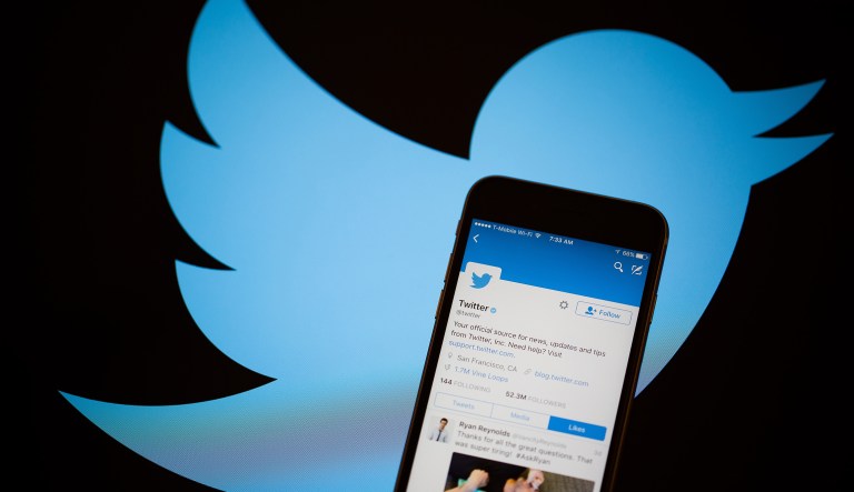The Twitter Inc. logo is seen behind an Apple Inc. iPhone 6s displaying the company's mobile application in this arranged photograph taken in New York, U.S., on Tuesday, Feb. 9, 2016. Twitter Inc. is changing its timeline to display popular tweets first, instead of the latest posts, a long-anticipated step thats likely to anger its most passionate users. Twitter is scheduled to report quarterly earnings results following the close of U.S. financial markets on February 10.