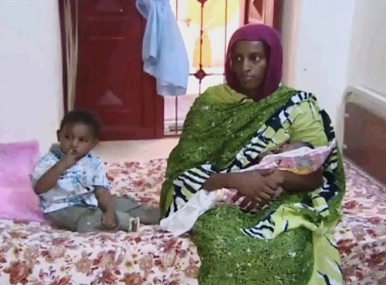 In this image made from an undated video provided Thursday, June 5, 2014, by Al Fajer, a Sudanese nongovernmental organization, Meriam Ibrahim, sitting next to Martin, her 18-month-old son, holds her newborn baby girl that she gave birth to in jail last week, as the NGO visits her in a room at a prison in Khartoum, Sudan. The Sudanese woman sentenced to death for refusing to recant her Christian faith after allegedly converting from Islam has appealed the sentence, her lawyer said. (AP Photo/Al Fajer)