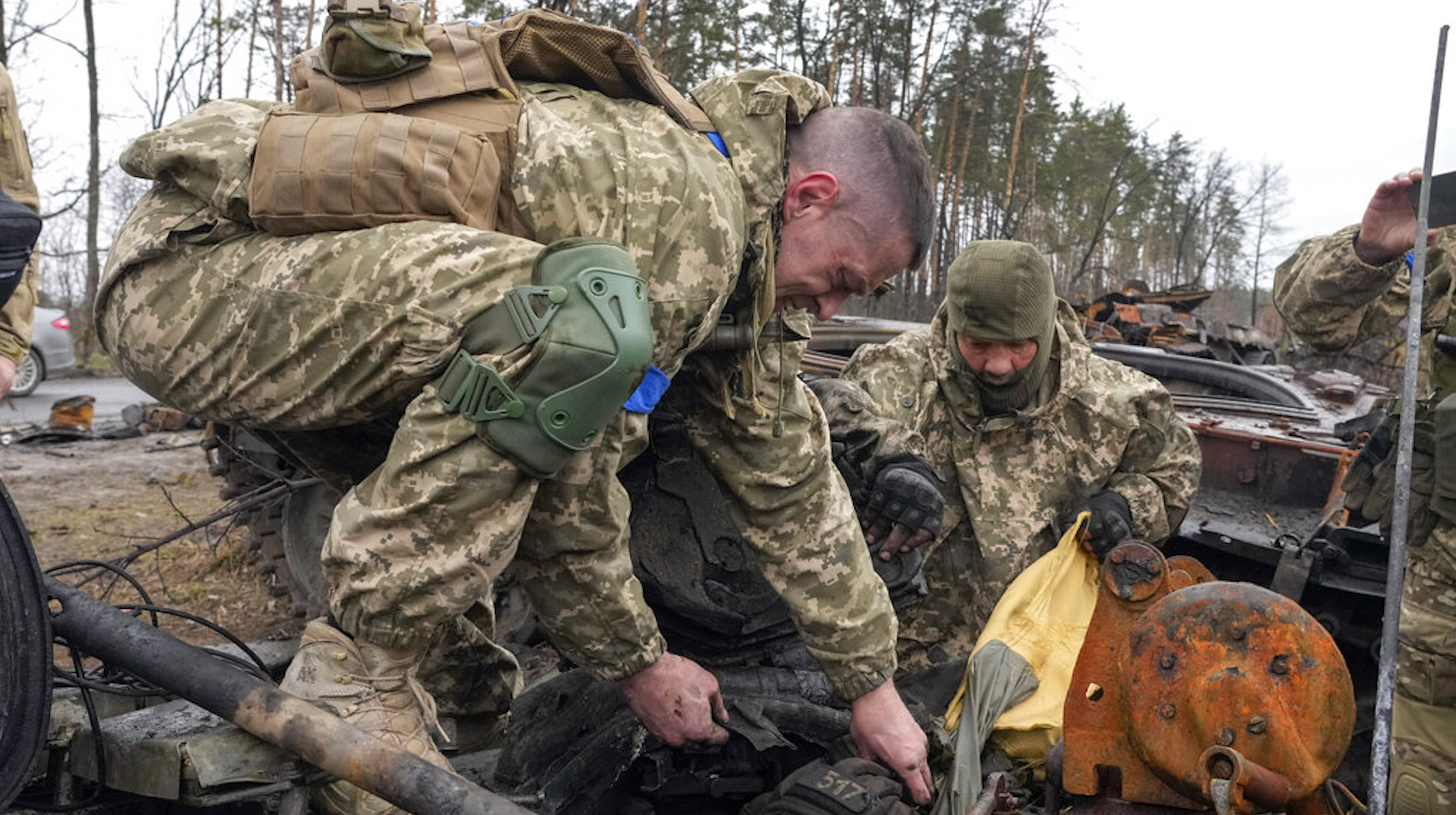 Ukrainian soldiers try to pull a dead body of a Russian soldier from the destroyed Russian tank in the village of Dmytrivka close to Kyiv, Ukraine, Saturday, Apr. 2, 2022. At least ten Russian tanks were destroyed in the fighting two days ago in Dmytrivka.