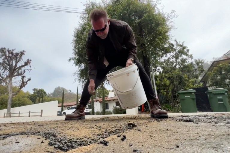 This video still image provided by The Office of Arnold Schwarzenegger shows former Gov. Arnold Schwarzenegger repairing a pot hole on a street in his Los Angeles neighborhood on Tuesday. Fed up by an enormous pothole in his neighborhood, Schwarzenegger picked up a shovel and filled it himself. 