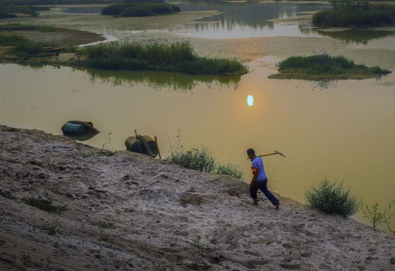 In this Tuesday, Aug. 19, 2014 photo, a farmer walks by a river in Pingdingshan in central China's Henan province. After a season of record-breaking drought across China, groundwater levels have hit historic lows this year in northeast and central parts of China where hundreds of millions of people live. Reservoirs grew so dry in agricultural Henan province that the city of Pingdingshan closed car washes and bathhouses and extracted water from puddles. (AP Photo) CHINA OUT