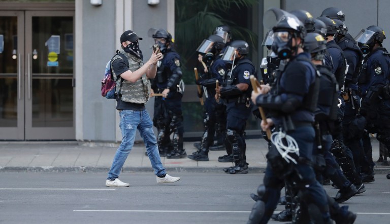 A protester walks with police officers during a protest over the deaths of George Floyd and Breonna Taylor, Saturday, May 30, 2020, in Louisville, Ky. Breonna Taylor, a black woman, was fatally shot by police in her home in March. 