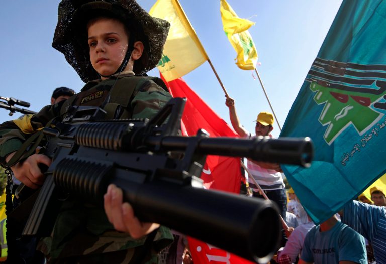 A Lebanese boy wearing a military uniform and holding a toy rifle attends a rally commemorating 