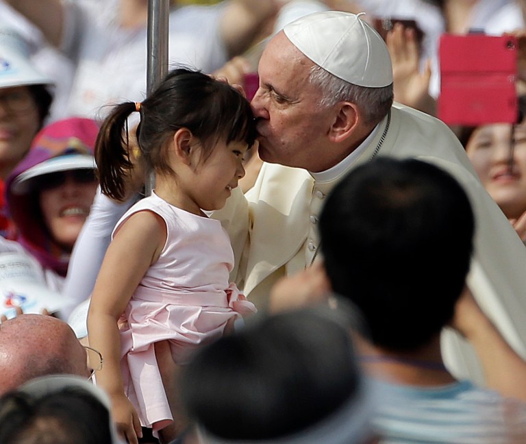 Pope Francis, right, kisses a girl as he arrives with the popemobile to celebrate a mass and the beatification Paul Yun ji-Chung and 123 martyr companions at Gwanghwamun Gate in Seoul, South Korea, Saturday, Aug. 16, 2014. Paul Yun Ji-Chung, born in 1759,  was among the earliest Catholics on the Korean Peninsula. (AP Photo/Gregorio Borgia)