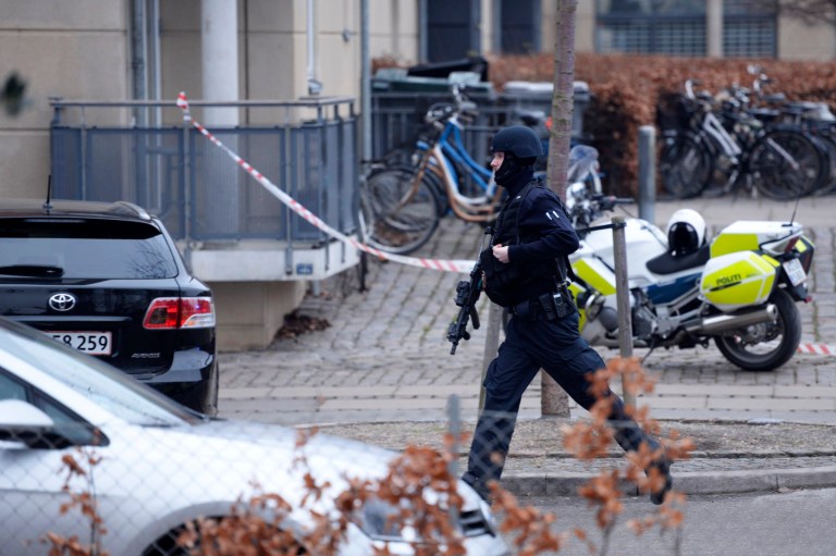 An armed security officer runs down a street near a venue after shots were fired where an event titled 