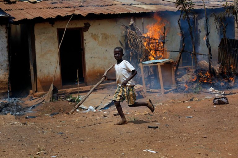 A child runs by a burning house as Anti-Balaka Christan youth loot the Muslim market in the PK13 district of Bangui, Central African Republic, Wednesday, Jan. 22, 2014. Hundreds of Anti-Balakas, helped by women and children, went on a rampage, burning and looting shops. Thirty civilian muslims, trapped inside their home, were later rescued by French forces assisted by Rwandan African Union peacekeepers. (AP Photo/Jerome Delay)