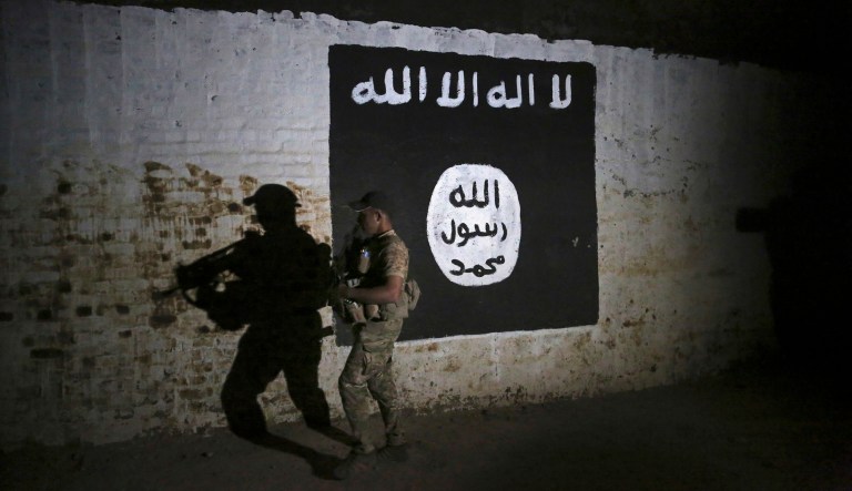 An Iraqi soldier inspects a recently-discovered train tunnel, adorned with an Islamic State group flag, that belonged to the former Baghdad to Mosul line, that was turned it to a training camp for IS fighters, in western Mosul, Iraq, Wednesday, March 1. 2017.