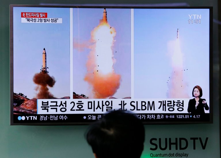 A man watches a TV news program showing photos published in North Korea's Rodong Sinmun newspaper of North Korea's 