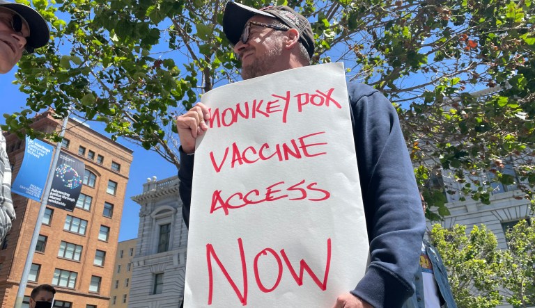 A man holds a sign urging increased access to the monkeypox vaccine during a protest in San Francisco, July 18, 2022. The Biden White House has enlisted veteran public health experts to lead the national monkeypox response. (AP Photo/Haven Daley, File)