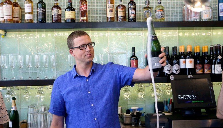 Andrew Cliburn opens a bottle of champagne at Current Fish and Oyster Saturday, July 1, 2017, in Salt Lake City, Utah. Among the provisions in the Craft Beverage Modernization and Tax Reform Act, included in the Republican tax bill, is the reduction of federal excise tax rates on beer, wine, and distilled spirits. (AP Photo/Rick Bowmer)