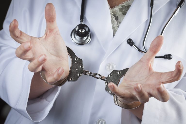 Doctor in handcuffs wearing lab coat and stethoscope