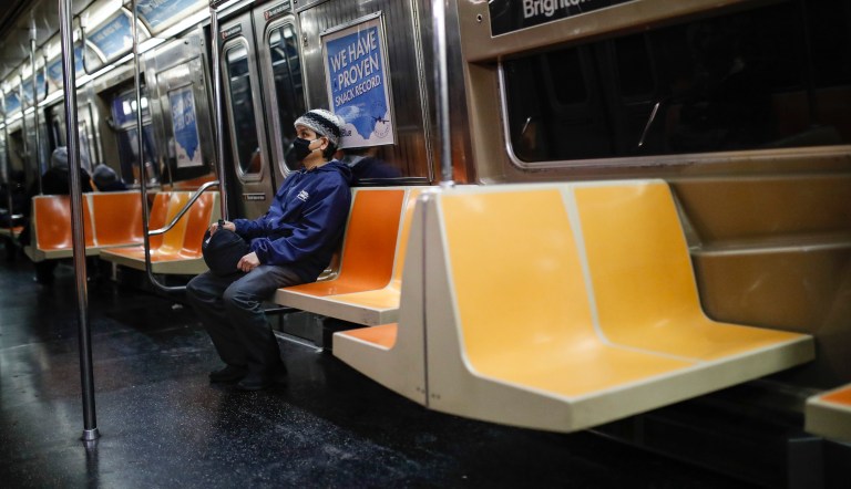 A commuter wears a face mask while riding the a nearly empty subway car into Brooklyn, Thursday, March 12, 2020, in New York. New York City Mayor Bill de Blasio said Thursday he will announce new restrictions on gatherings to halt the spread of the new coronavirus in the coming days. (AP Photo/John Minchillo)
