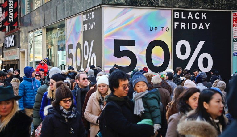 Crowds walk past a large store sign displaying a Black Friday discount in midtown Manhattan, Friday, Nov. 23, 2018, in New York. While Black Friday may no longer look like the crowd-filled, in-person mayhem that it was just decades ago â in large part due to the rising dependence on online shopping that was accelerated by the COVID-19 pandemic â the holiday sales event is still slated to attract millions of consumers.