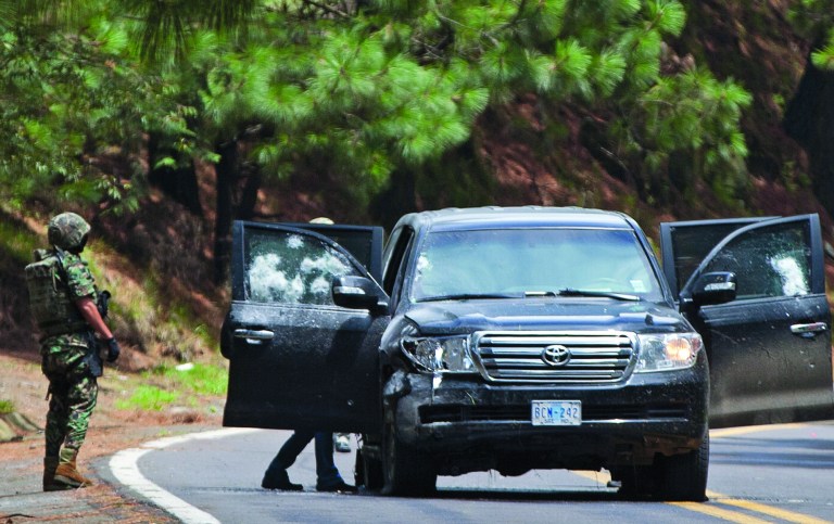FILE - In this Aug. 24, 2012. file photo, an armored U.S. embassy vehicle is checked by military personal after it was attacked by unknown assailants on the highway leading to the city of Cuernavaca, near Tres Marias, Mexico. A senior U.S. official says there is strong circumstantial evidence that Mexican federal police who fired on a U.S. embassy vehicle, wounding two CIA agents, were working for organized crime on a targeted assassination attempt. (AP Photo/Alexandre Meneghini, File)