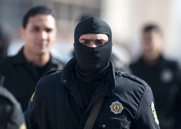 A hooded member of the Tunisian anti-terrorist police forces (BAT) walks near a house where suspected Islamist militants were hidden in Raoued, near Tunis, Tuesday, Feb. 4, 2014. Tunisia's police exchanged gunfire with a group of suspected Islamic militants holed up in a house in a suburb near the capital on Tuesday, leaving two militants and a policeman dead, an Interior Ministry spokesman said Tuesday. (AP Photo/Aimen Zine)