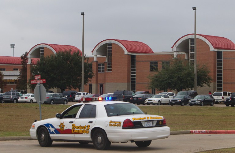   A police vehicle is parked near the entrance of North Shore High School after a shooting occurred Wednesday, Dec. 5, 2012, in Houston. Police say a high school student shot himself while in the back of a patrol car after being arrested earlier on suspicion of taking a gun to campus. (AP Photo/Houston Chronicle, Cody Duty)  