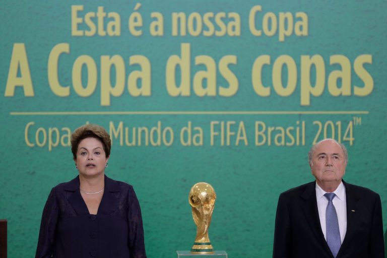 FILE - In this June 2, 2014, file photo, Brazil's President Dilma Rousseff and FIFA President Joseph Blatter stand during the playing of the Brazilian national anthem during a ceremony where Blatter presented the 2014 World Cup trophy to Rousseff, at Planalto presidential palace, in Brasilia, Brazil. For Rousseff, who has seen her approval rating steadily fall as she gears up for a re-election run, hosting the World Cup has become a potential political liability reminding voters of her failure to deliver on promises and live up to a reputation for being a hard-driving manager. (AP Photo/Eraldo Peres,File)