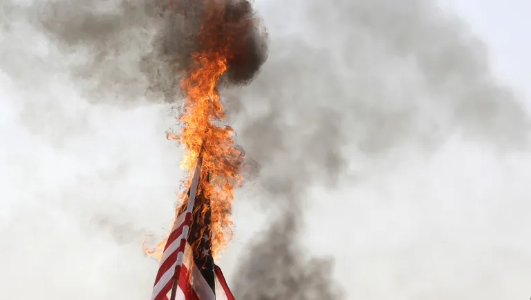 Palestinian protesters burn an American flag during a protest at the Gaza Strip's border with Israel on April 6, 2018.