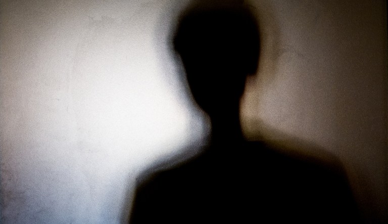 A person's shadow on frosted glass.