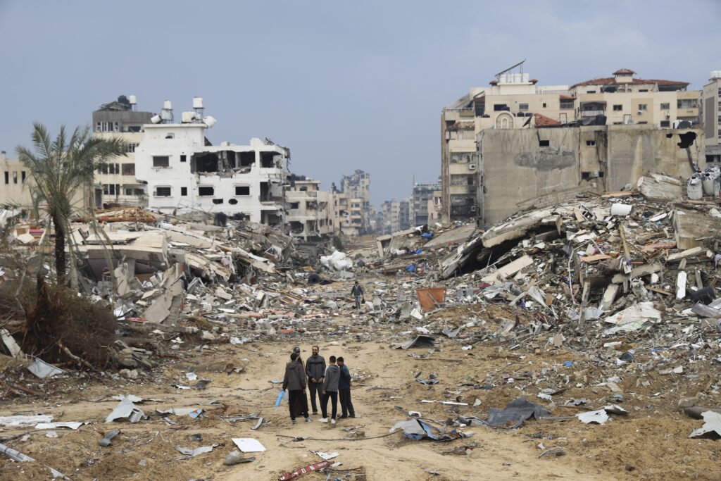 Palestinians walk past the building destroyed in the Israeli Bombardment of the Gaza Strip in Gaza City on Wednesday, Jan. 3, 2024.