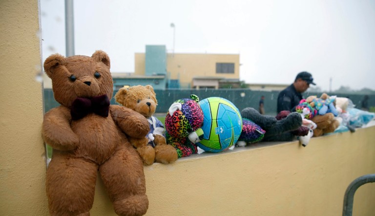In this Saturday, June 23, 2018, photo, a guard walks by toys placed for migrant children by protesters as they march to Homestead Temporary Shelter for Unaccompanied Children, in Homestead, Florida.