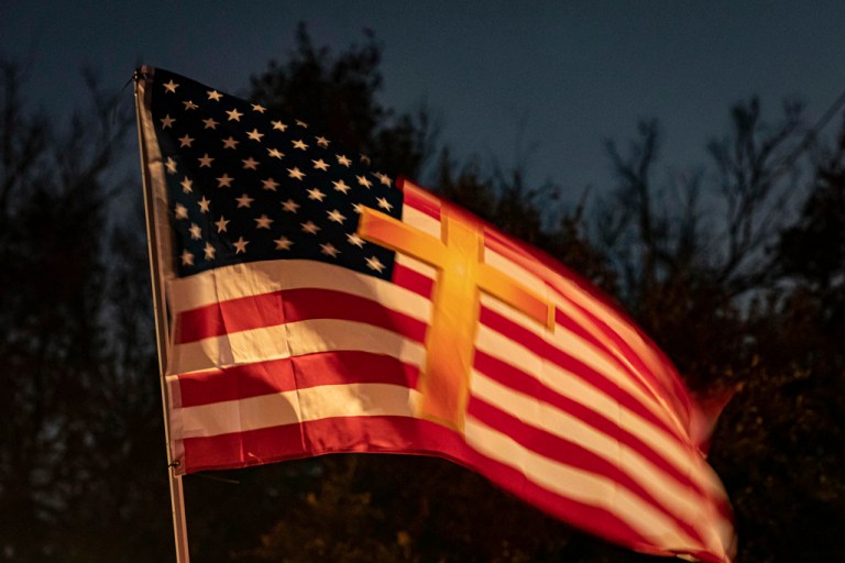 An American flag with a cross on it waves above the crowd during the 