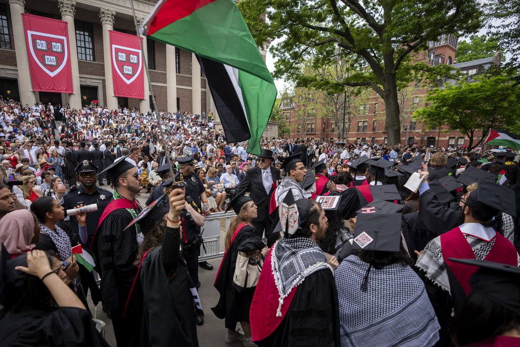 Graduating students hold Palestinian flags and chant as they walk out in protest over the 13 students who have been barred from graduating due to protest activities, during commencement in Harvard Yard, at Harvard University, in Cambridge, Mass., Thursday, May 23, 2024.