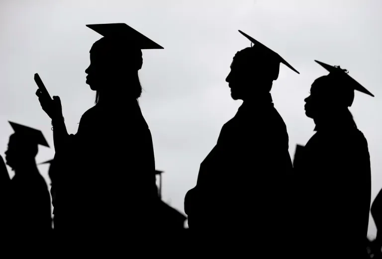 New graduates line up before the start of a community college commencement