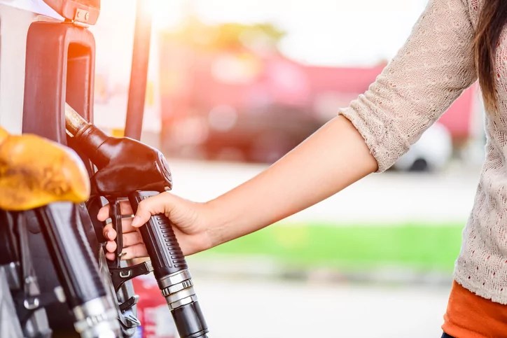 Closeup of woman hand holding a fuel pump at a station.