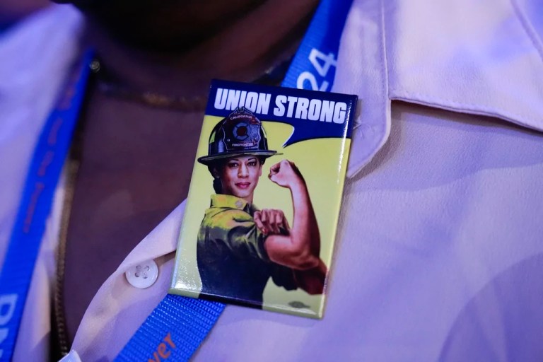 A delegate wears a pin that says 