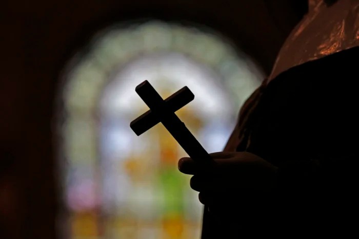 This Dec. 1, 2012 file photo shows a silhouette of a crucifix and a stained glass window inside a Catholic Church in New Orleans. On Thursday, Sept. 7, 2023, a Louisiana state grand jury charged a now-91-year-old disgraced priest, Lawrence Hecker, with sexually assaulting a teenage boy in 1975, an extraordinary prosecution that could shed new light on what Roman Catholic Church leaders knew about a child sex abuse crisis that persisted for decades and claimed hundreds of victims.