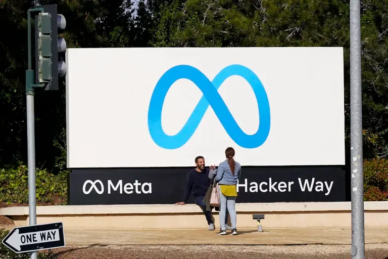 People talk near a Meta sign outside of the company's headquarters in Menlo Park, California, March 7, 2023. Meta's Oversight Board said Monday, Feb. 5, 2024, that it is urging the company to clarify its approach to manipulated media so its platforms can better beat back the expected flood of online election disinformation this year. The recommendations come after the board reviewed an altered video of President Joe Biden that was misleading but didn't violate the company's policies. (AP Photo/Jeff Chiu)