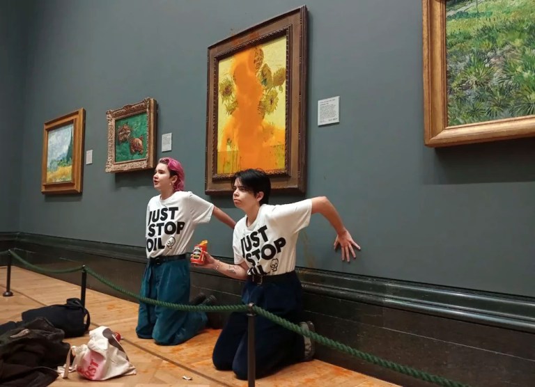 This photo provided by Just Stop Oil shows two protesters who have thrown tinned soup at Vincent Van Gogh's famous 1888 work Sunflowers at the National Gallery in London, Oct. 14, 2022.
