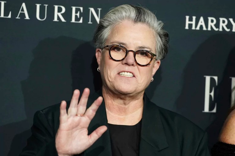 Rosie O'Donnell waves while smiling.