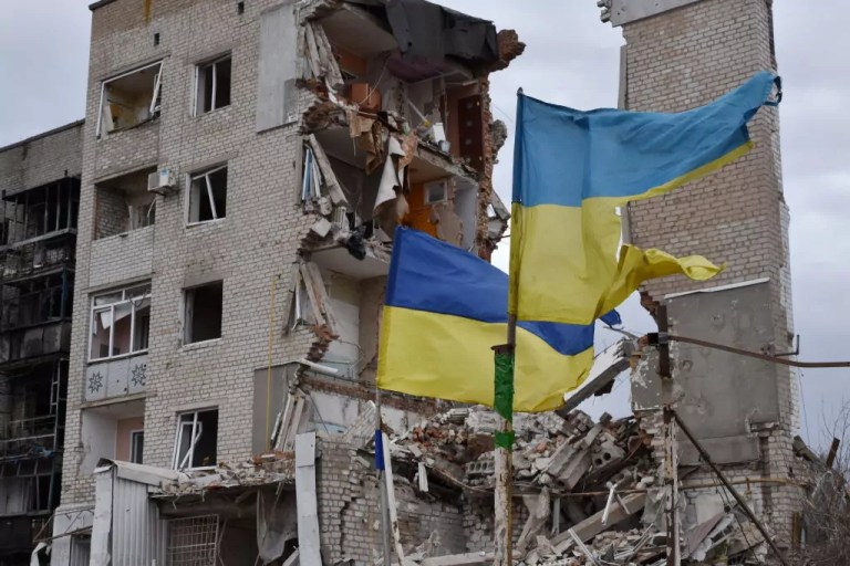 Ukrainian flags seen by an apartment building heavily damaged by Russian shelling.