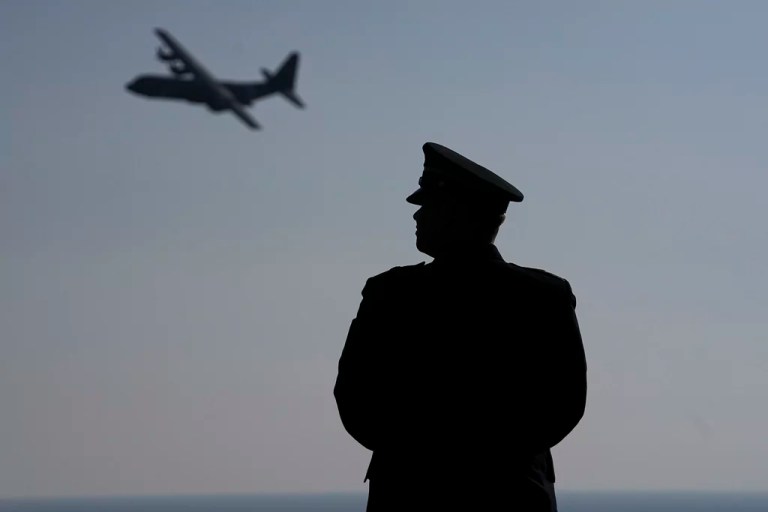 A participant watches as a plane flies past during a ceremony near Colleville-sur-Mer Normandy, Thursday, June 6, 2024. World War II veterans from across the United States as well as Britain and Canada are in Normandy this week to mark 80 years since the D-Day landings that helped lead to Hitler's defeat. (AP Photo/Laurent Cipriani)