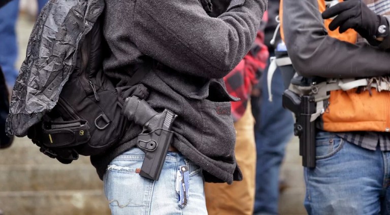 Men stand with pistols strapped at their sides at a gun rights rally on the steps of the Capitol Friday, Jan. 15, 2016, in Olympia, Wash. Lawmakers and others spoke at the rally, which drew about 100 people, emphasizing legislative priorities and speaking against gun-related policies of President Barack Obama, like his recent executive actions to expand background checks to cover more firearms sold at gun shows, and elsewhere.