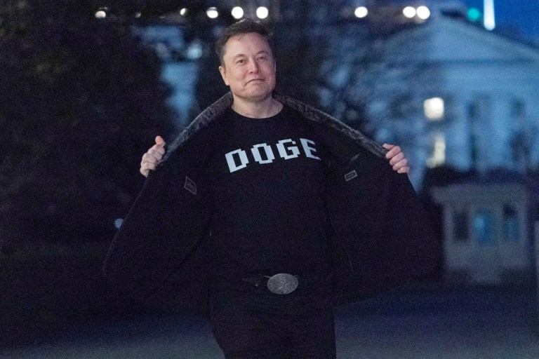 Elon Musk flashes his t-shirt that reads 