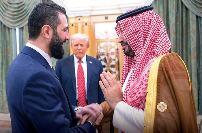 President Donald Trump, center, looks to Saudi's Crown Prince Mohammed bin Salman, right, shake hands with Syria's interim President Ahmad al Sharaa.