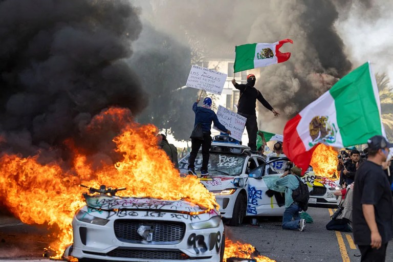 Protesters against Trump's mass deportation policies wave Mexican flags after setting cars on fire in Los Angeles, California, on June 8, 2025. (Ringo Chiu / AFP via Getty Images)
