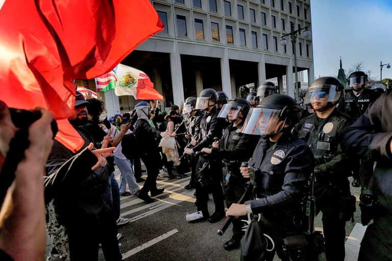 Los Angeles police in riot gear form a skirmish line and push back protesters down a street away from a federal building in downtown Los Angeles on Monday, June 9, 2025.