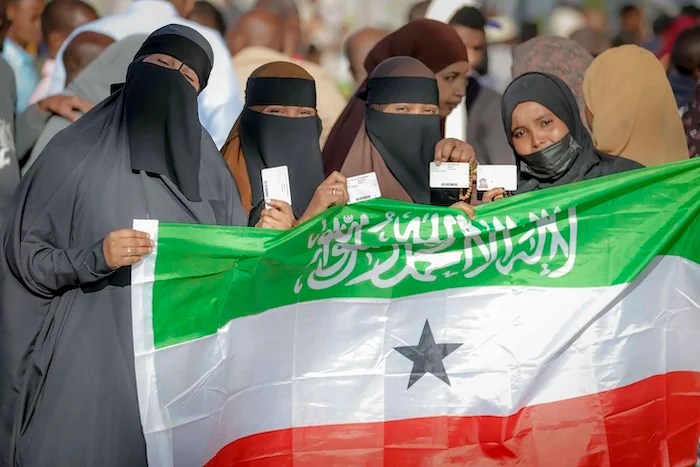 People display the Somaliland flag as they wait to cast their vote in 2024.