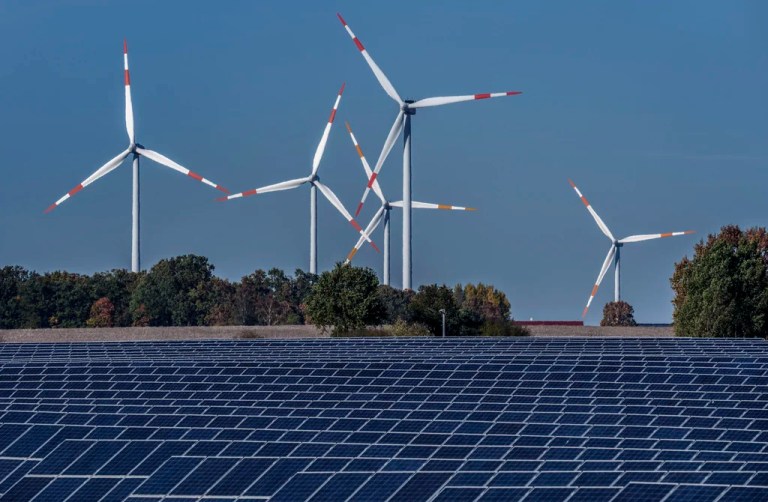 Wind turbines turn behind a solar farm in Rapshagen, Germany, Oct. 28, 2021. European Union lawmakers endorsed a deal Tuesday to raise the share of renewables in the bloc’s energy mix, another step to accelerate its green transition away from fossil fuels. The bill, adopted by a large majority — 470 lawmakers voted in favor, 120 against and 40 abstained — foresees an updated renewable energy target of 42.5% of total consumption by 2030. The current goal is 32%. (AP Photo/Michael Sohn, File)