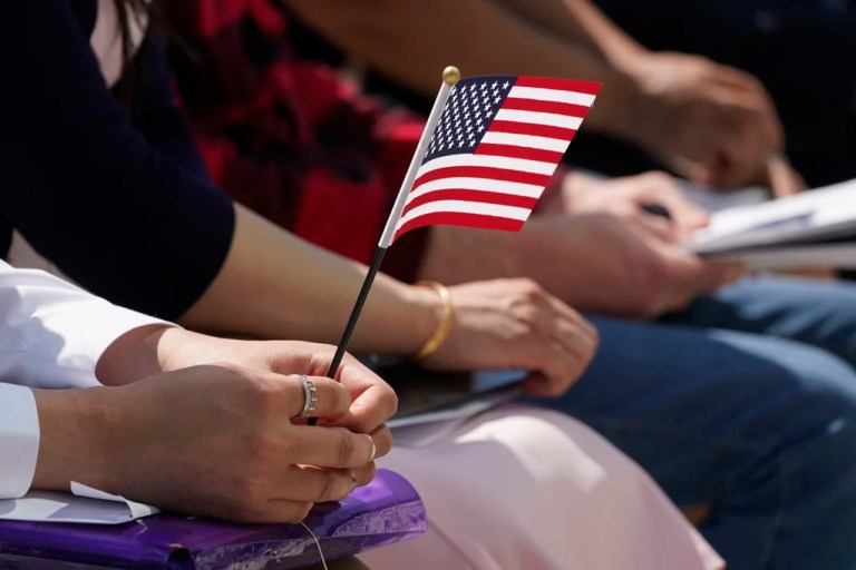 A new citizen holds the American flag during a Naturalization Ceremony at Indianapolis Motor Speedway, May 17, 2022, in Indianapolis.