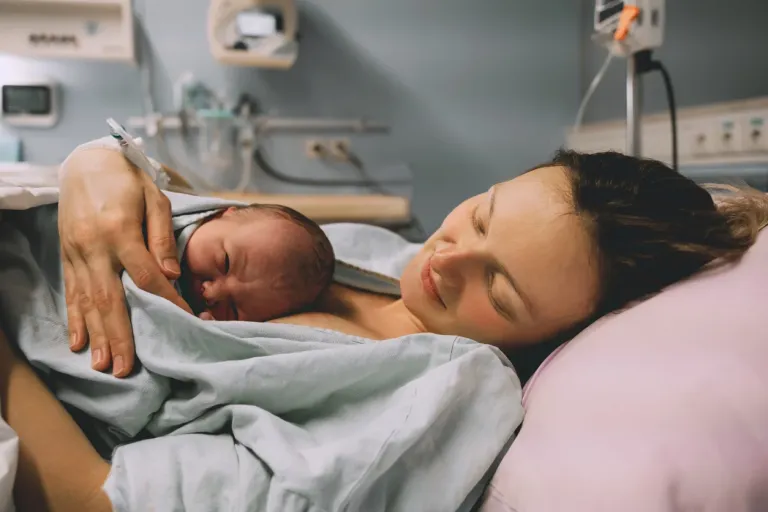 A mother holds her baby on her chest after giving birth.