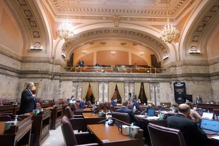 Sen. Mike Padden, R-Spokane Valley, left, speaks as other senators are spread out at desks on the Senate floor and into an upper gallery Monday, Jan. 11, 2021, at the Capitol in Olympia, Wash. Washington state's Legislature convened Monday under a large security presence because of concerns about efforts by armed groups who might try to disrupt the proceedings or occupy the Capitol, which is closed to the public due to the ongoing pandemic.